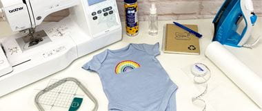 Blue babygrow with embroidered rainbow and Brother M330e embroidery machine