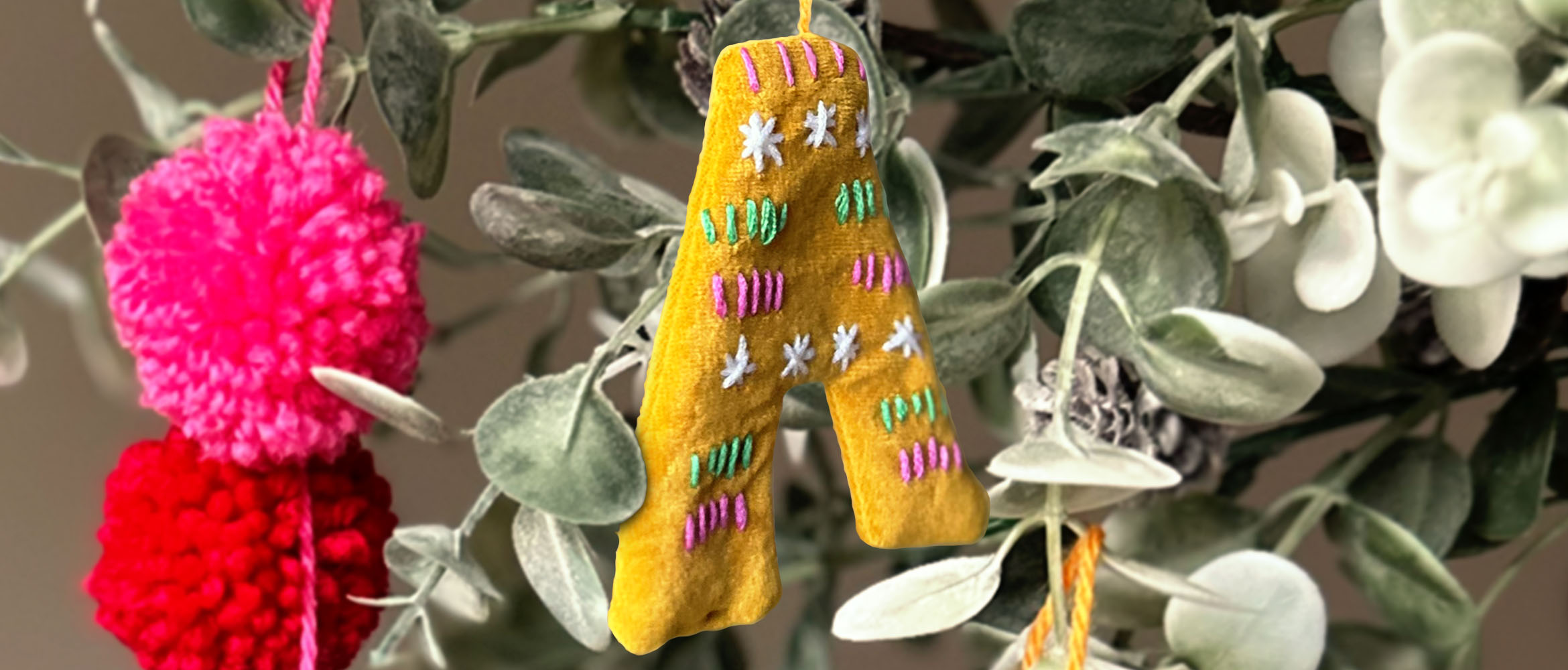 Embroidered fabric letter A hanging in a plant