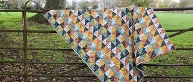 Autumnal half square triangles Quilt on fence