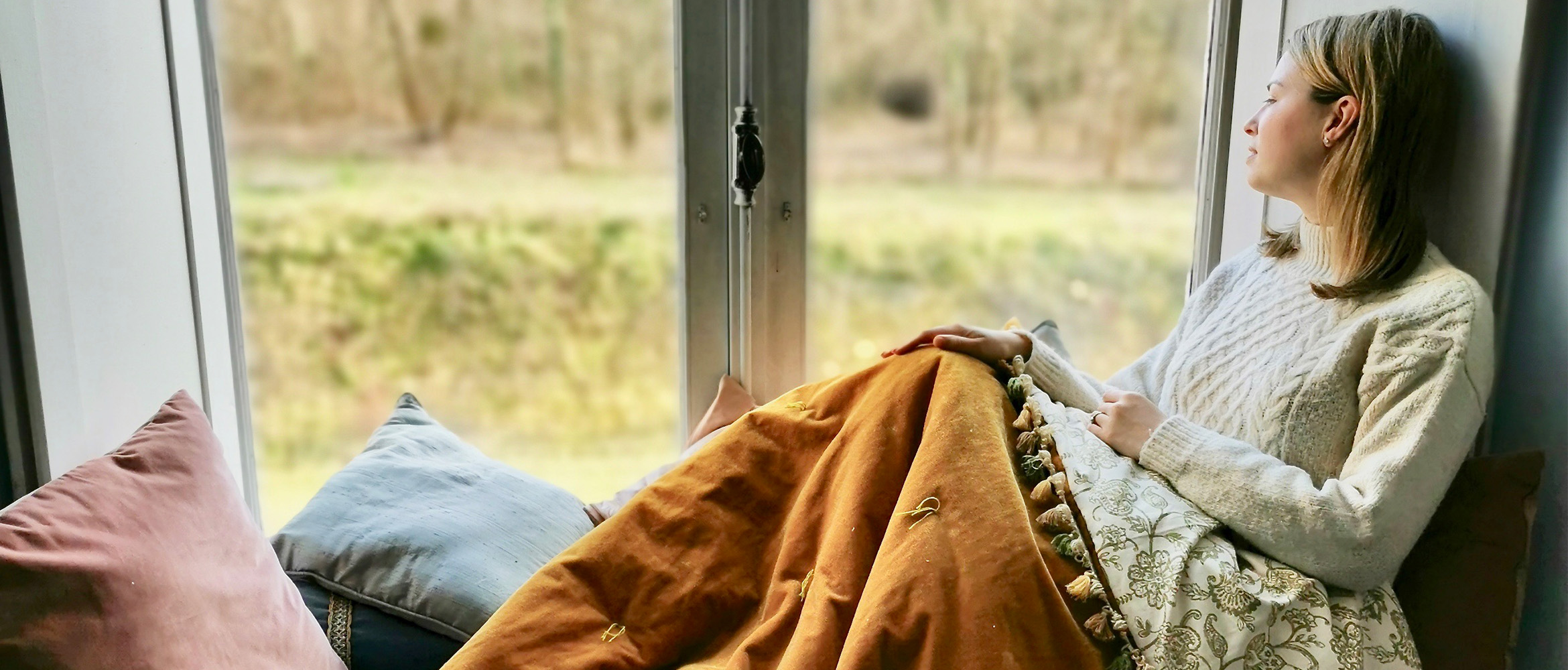 Frau mit Samtüberwurf am Fenster sitzend