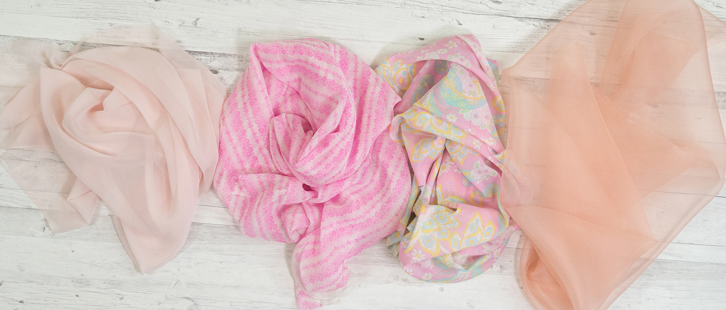 Sheer fabrics rolled into bundles on wooden background