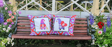 Two colourful love gnome cushions on park bench
