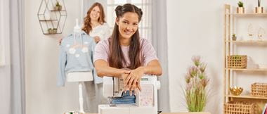 young woman in pink shirt leaning on Brother Innov-is KD40s sewing machine smiling