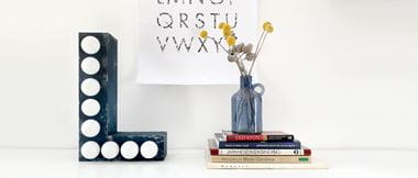 Black capital letter L with lightbulbs on desk with books