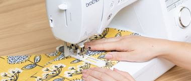 Vrouw naait knoopsgat op gele stof
