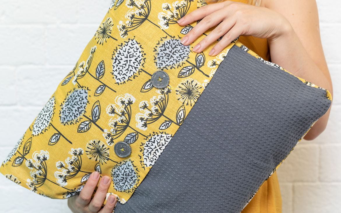 Hands holding yellow and grey cushion