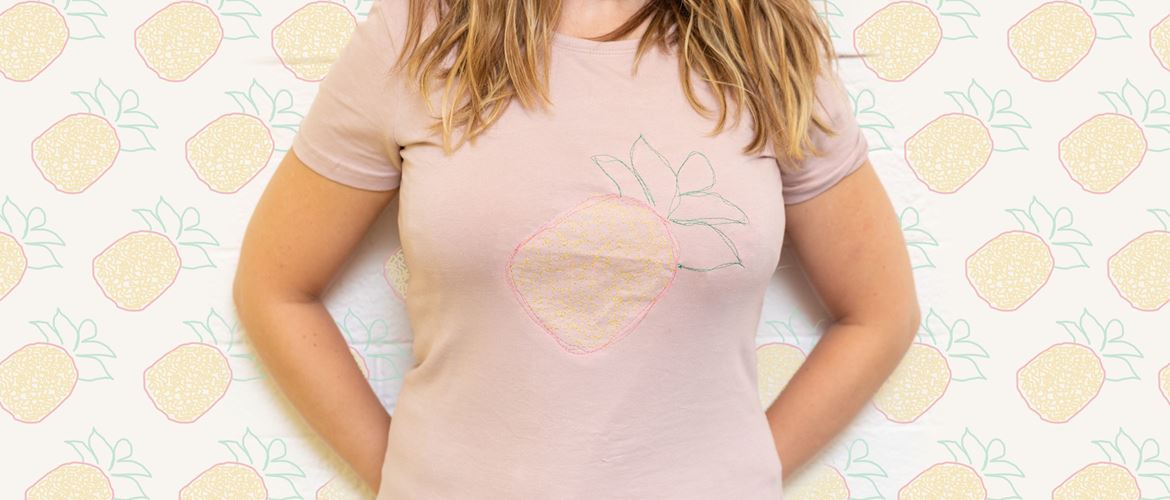 Woman wearing pink t-shirt with embroidered pineapple on front