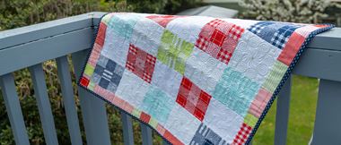quilt made of small squares hanging over fence