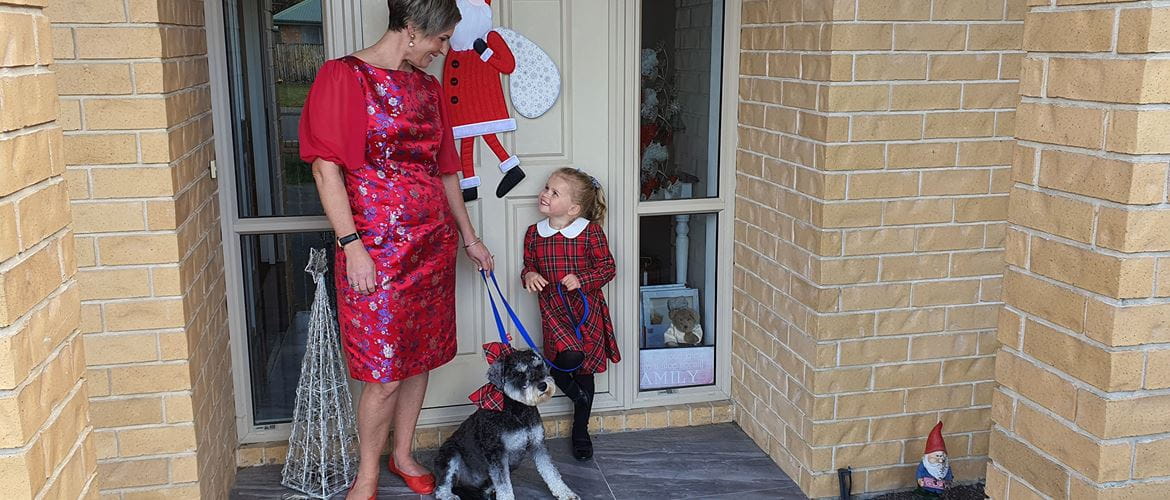 Mutter und Tochter auf der Türschwelle in roten Kleidern mit Hund