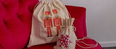 Two reusable embellished wrapping bags on a red sofa