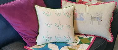 Cushions with festive embroidery and colorful quilt on sofa