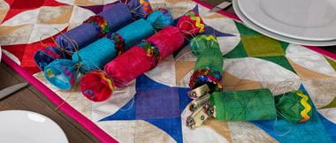 colorful reusable christmas crackers sewn from fabric on a desk