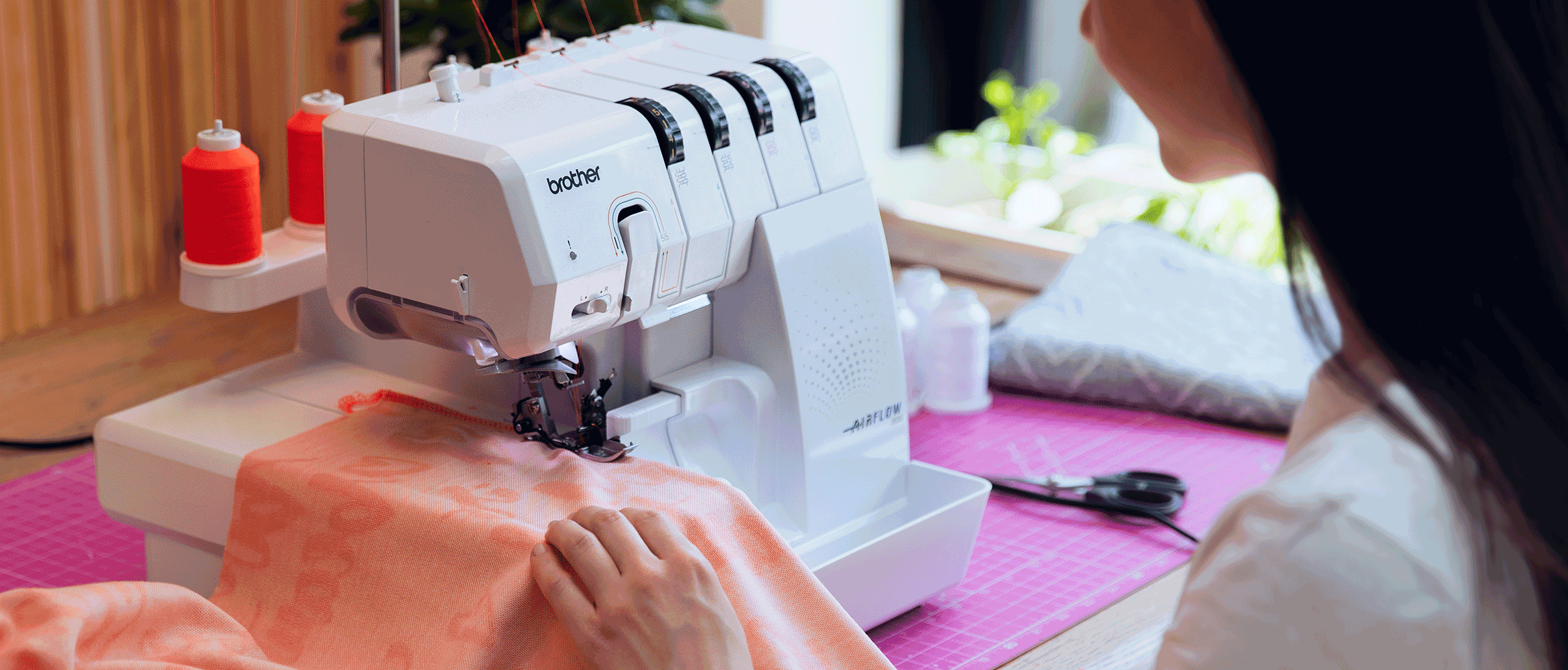 Vrouw naait oranje stof met Brother Airflow 3000 overlockmachine