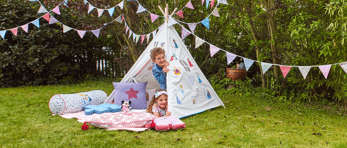 Girl and boy peaking out of tent embroidered with Disney designs