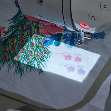 Embroidery designs projected next to embroidery on white fabric