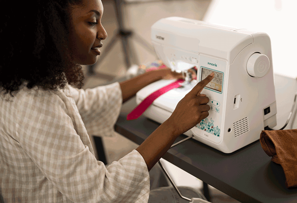 donna modifica le impostazioni sulla macchina da cucire Brother F560