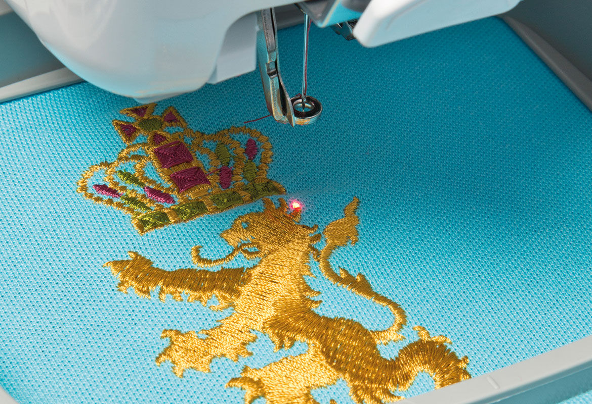 Rode LED-pointer op gouden geborduurde leeuw op blauwe stof