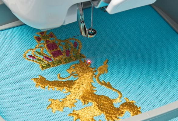 Red LED pointer on golden embroidered lion on blue fabric