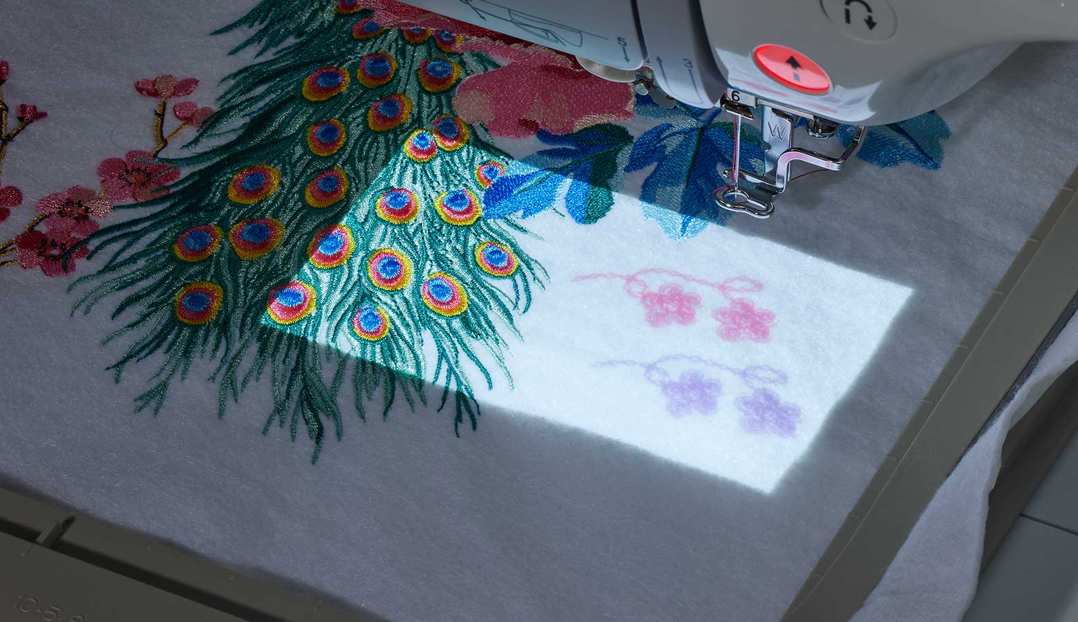 Embroidery designs projected next to embroidery on white fabric
