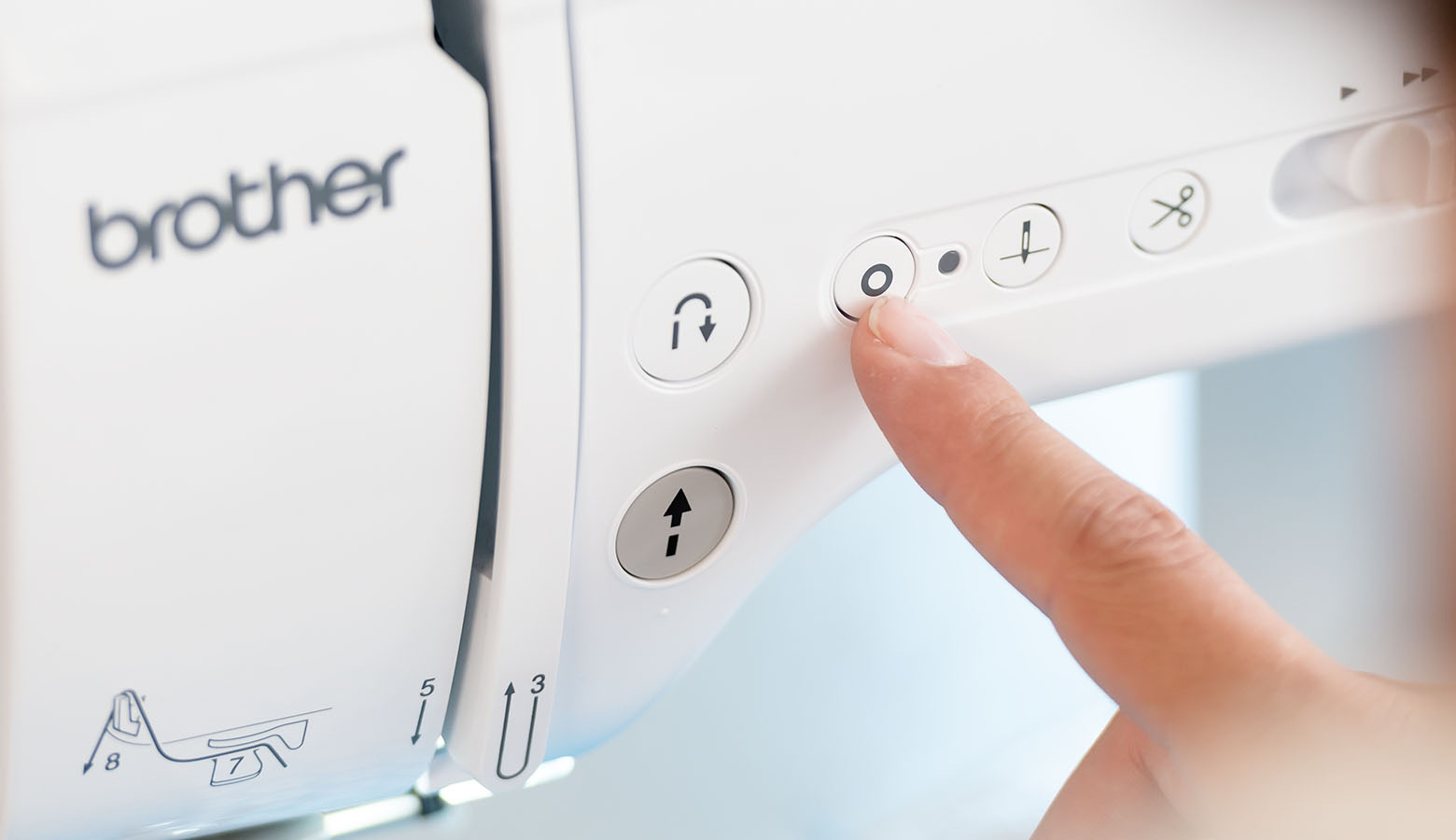 vinger die op de locksteekknop drukt op de Brother A-serie naaimachine