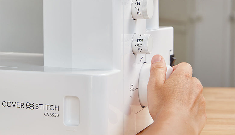 hand die reikt naar de bediening van de Brother-coverstitch-machine