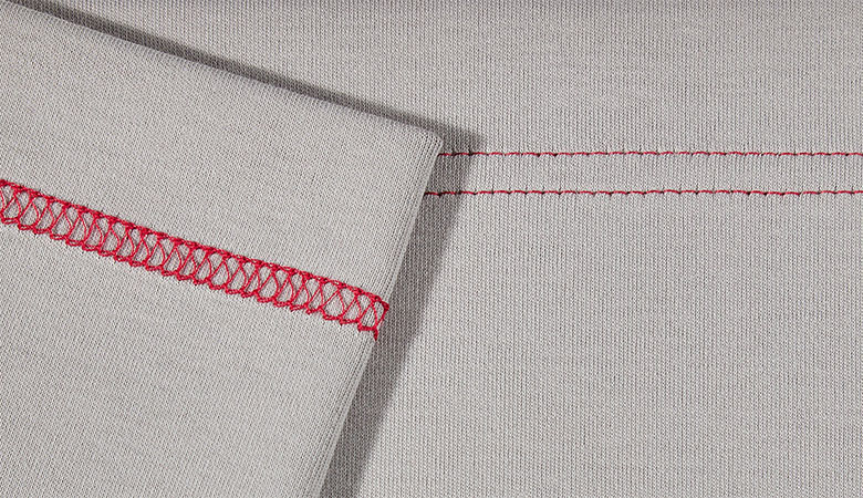 Gros plan du point de recouvrement large rouge sur tissu gris