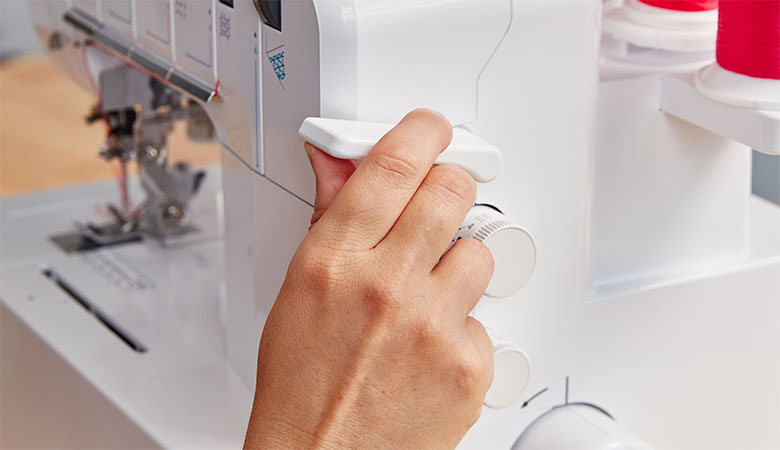 Hand am Nähfußhebel der Brother Coverstichmaschine