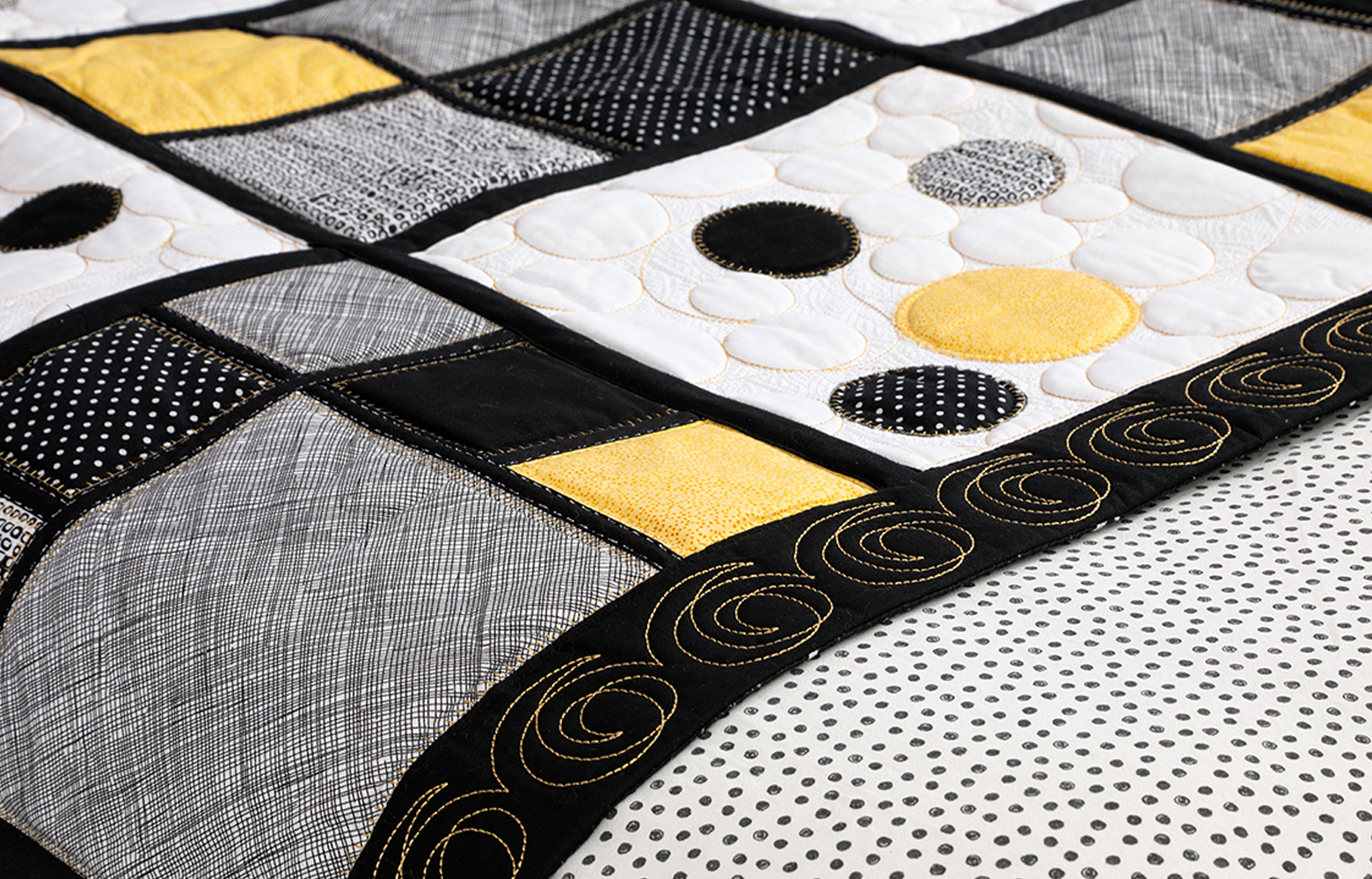 close-up van zwart, geel en grijs quilt bedrunner