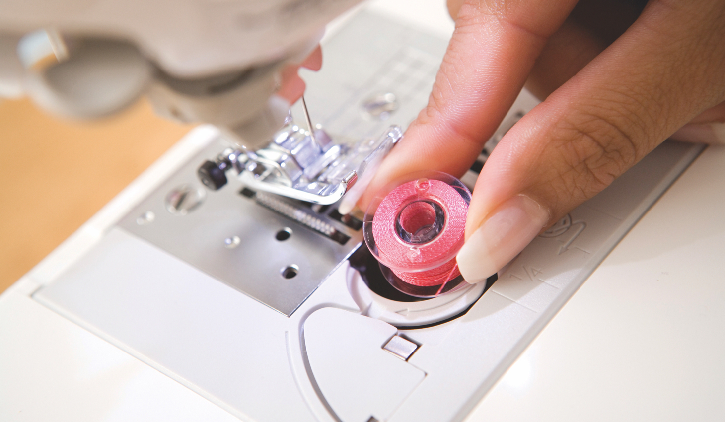 someone replacing the bobbin on a sewing machine