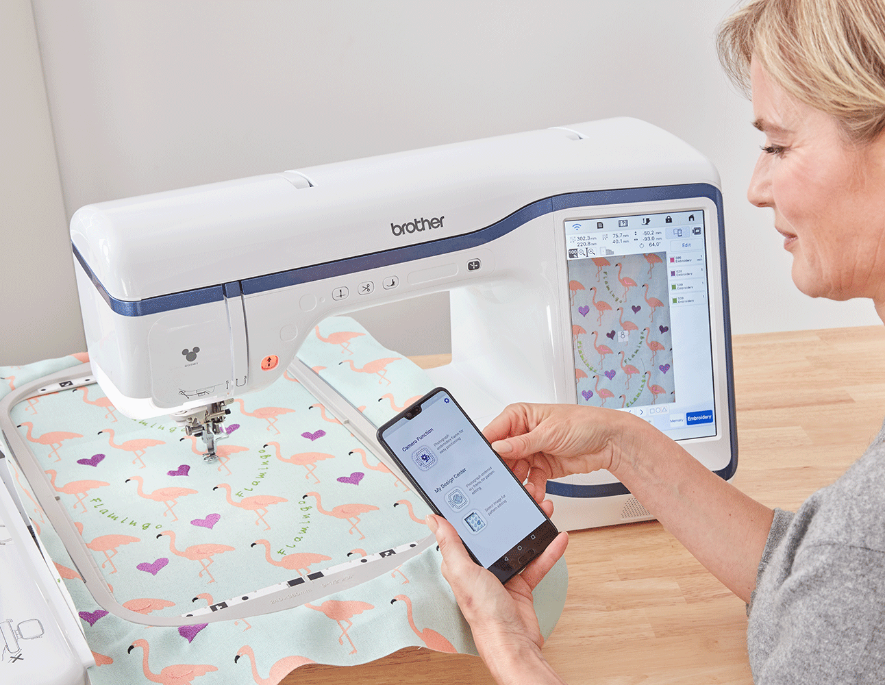 Lady holding phone with My Design Snap and Stellaire embroidery machine