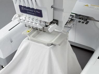 Camicia bianca in un telaio magnetico in macchina da ricamo