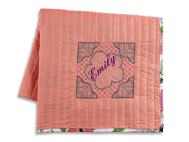 Coral colour quilt with Emily embroidered design in blue and purple