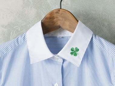 Trèfle vert brodé sur le col d’une chemise blanche
