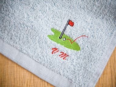 Blue golf towel with embroidery of golf green
