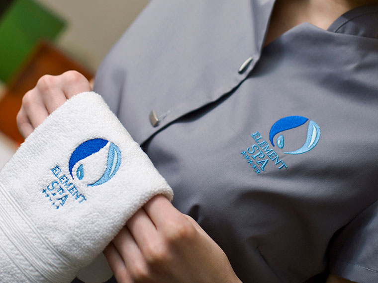 Graues Hemd und weißes Handtuch mit Sticklogos