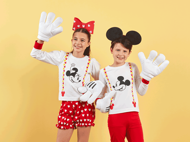 Boy and girl in their Mickey Mouse outfits infront of a yellow wall