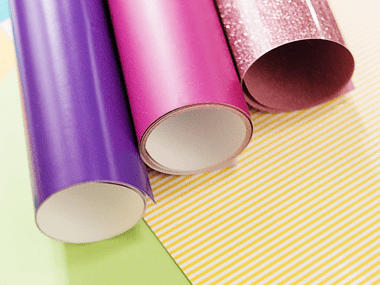 Pink and purple rolls of vinyl on yellow cardboard