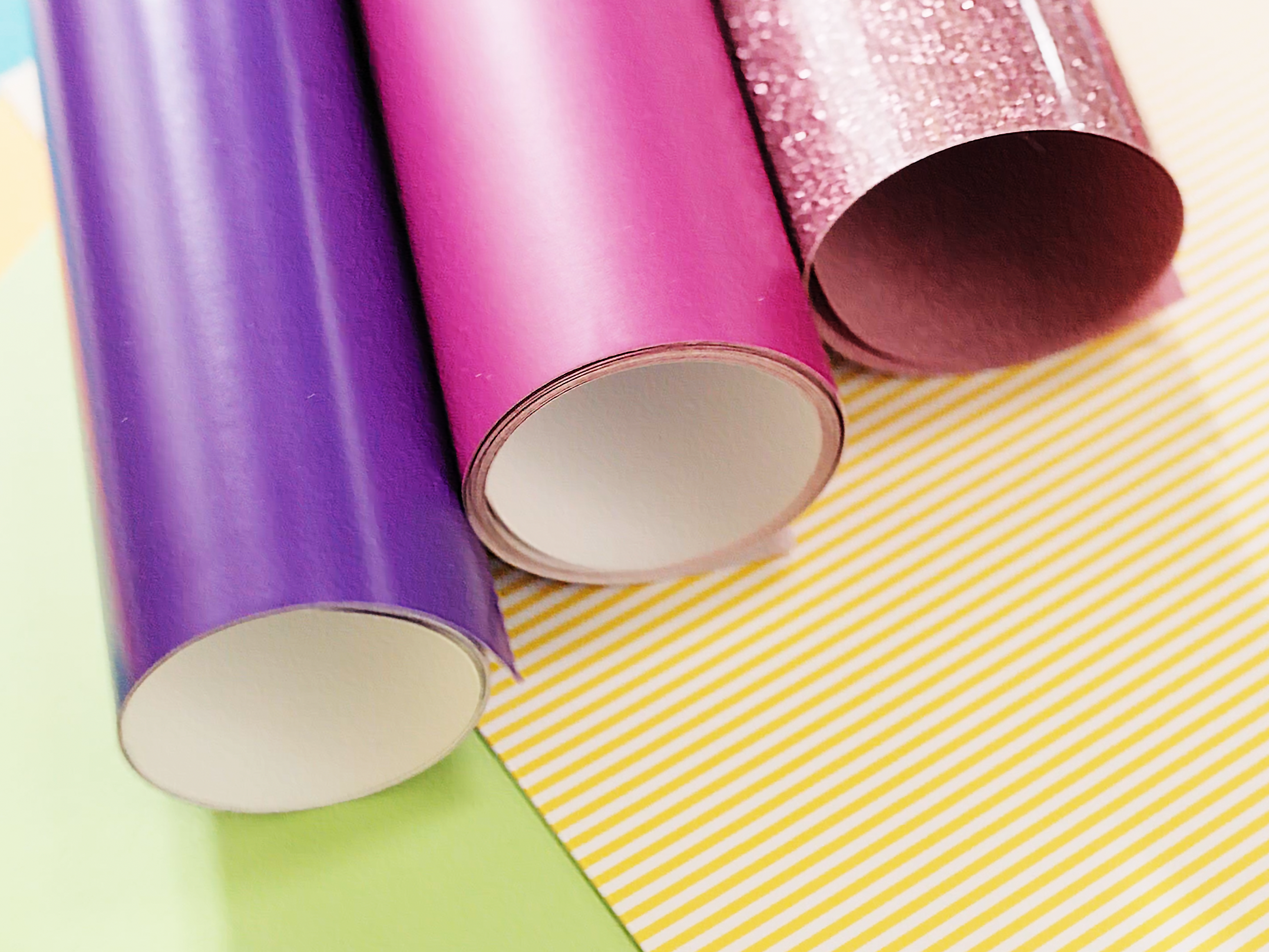 Pink and purple rolls of vinyl on yellow cardboard