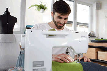 Young man sewing a blue and green project.