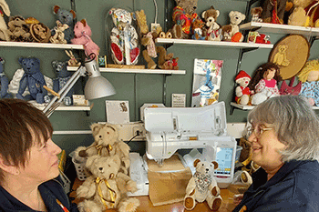 Two ladies with many teddybears around them.