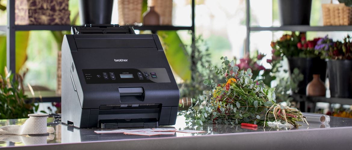 HAK hot foil printer, standing on table in flower shop, printed greeting cards and bouquet of flowers next to it